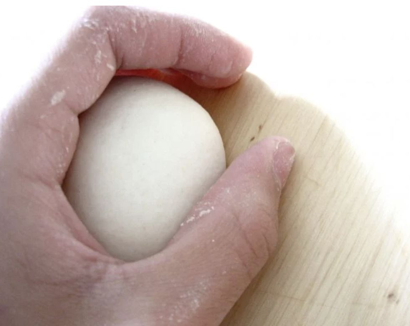 step 6 Now, take a dough ball, and press it gently against the countertop (or whatever work surface you’re using) moving your hand and the ball in a circular motion pulling the dough into itself while reducing the pressure on top of the dough slightly until a perfect dough ball forms.