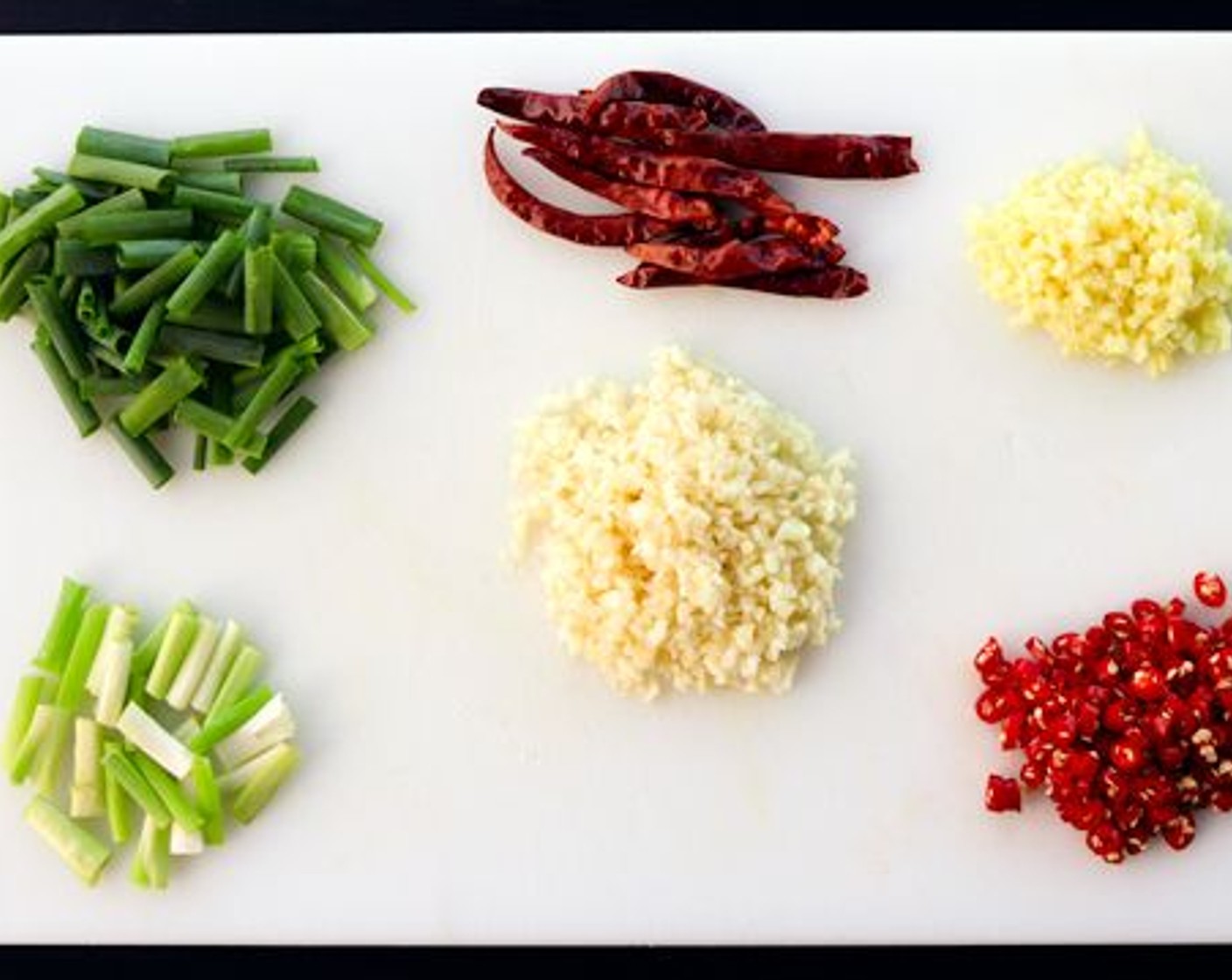 step 1 Add the Garlic (7 cloves), Fresh Ginger (2 Tbsp), and Scallion (1 bunch) whites to a small bowl. Add your Red Chili Peppers (5) and spring onion greens into two separate small bowls.