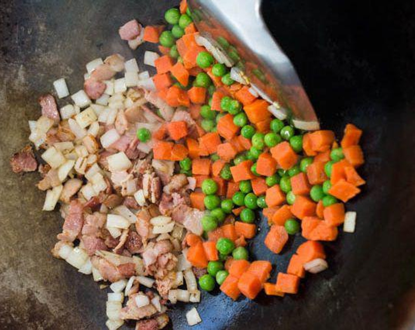 step 5 Add chopped Onion (1/2) to the wok. Stir-fry until the onion turns slightly translucent, then add the Frozen Peas and Carrots (1/3 cup). Stir-fry for about 1 minute.