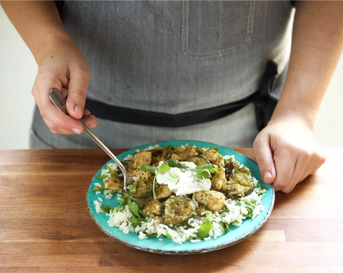 step 26 In the center of two places, place the spinach garlic rice. Add the chicken verde on top of the rice. Spoon Sour Cream (2 Tbsp) on top. Garnish with cilantro sprigs.