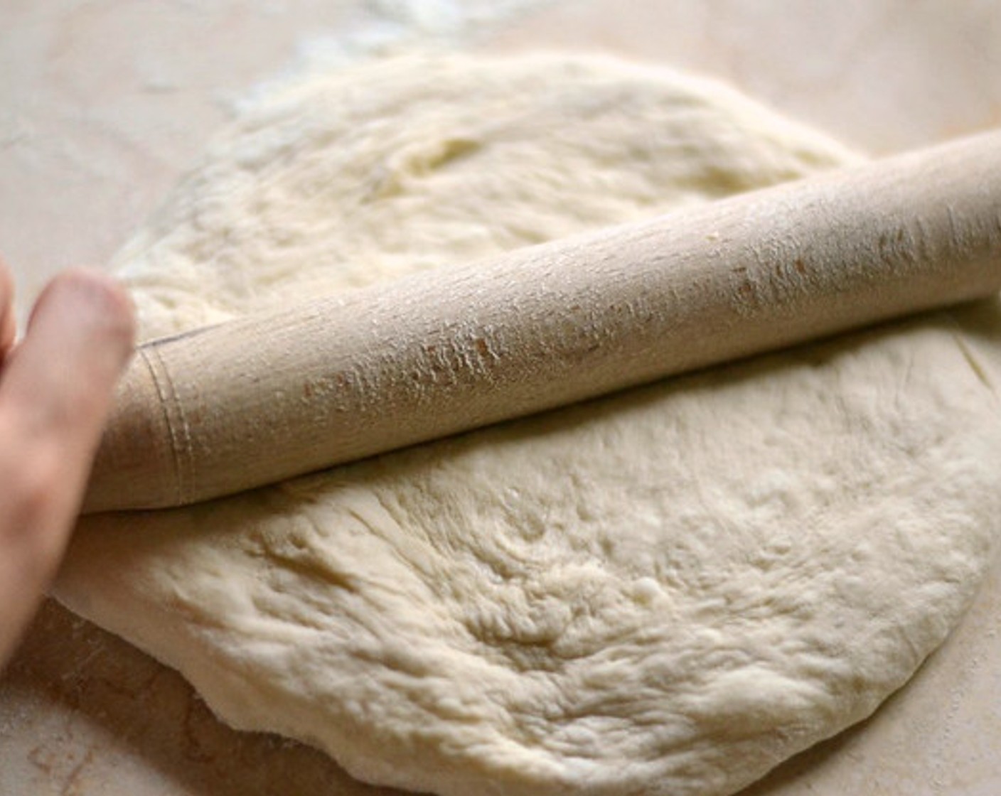 step 2 Flatten your Pizza Dough (1/2) into a roundish shape by hand and continue with a rolling pin.