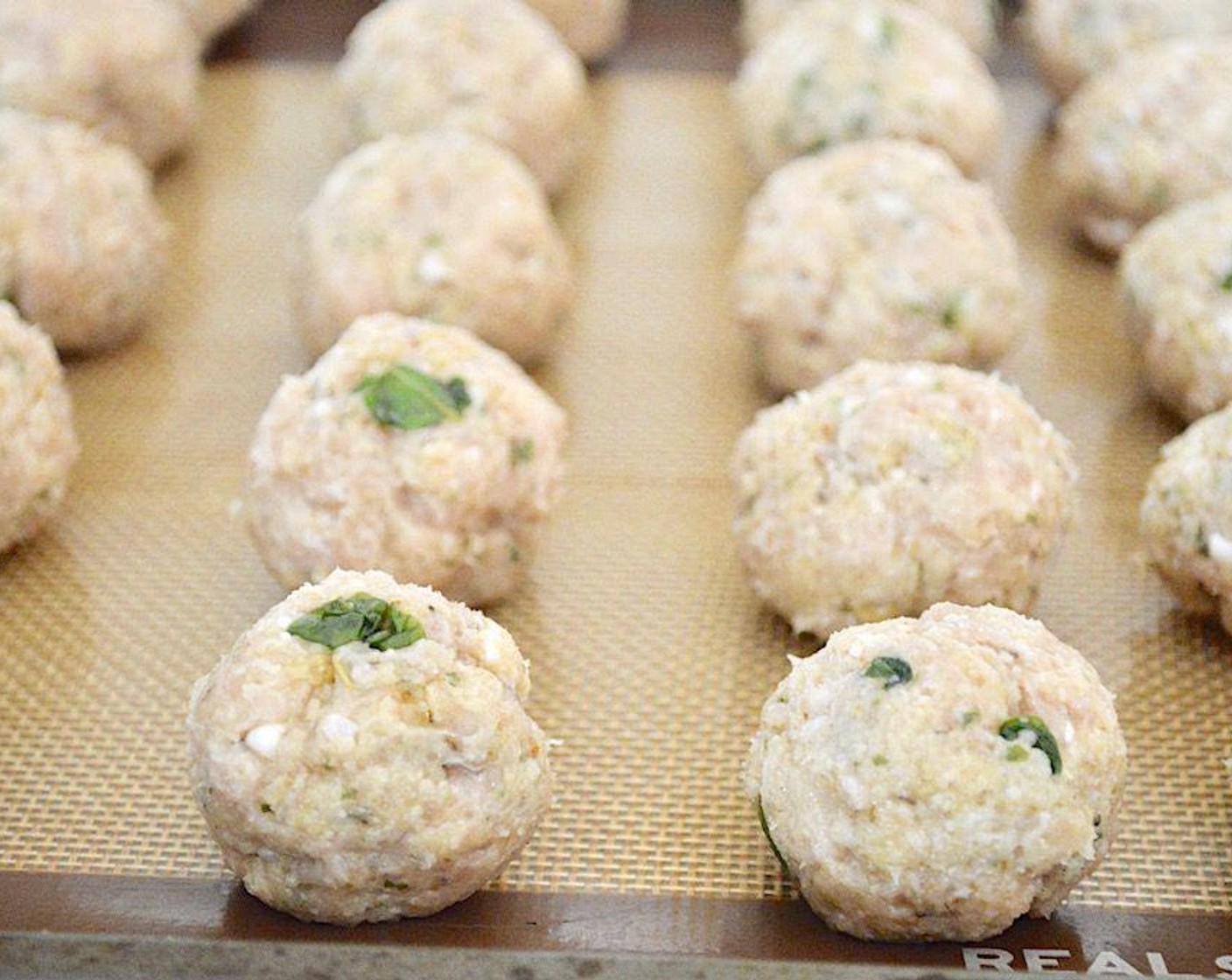 step 3 Form the mixture into 20 or so smaller meatballs and lay them out on the sheet tray. Bake them for 20-25 minutes, until golden on the outside and cooked through. While they bake, get the sauce simmering.