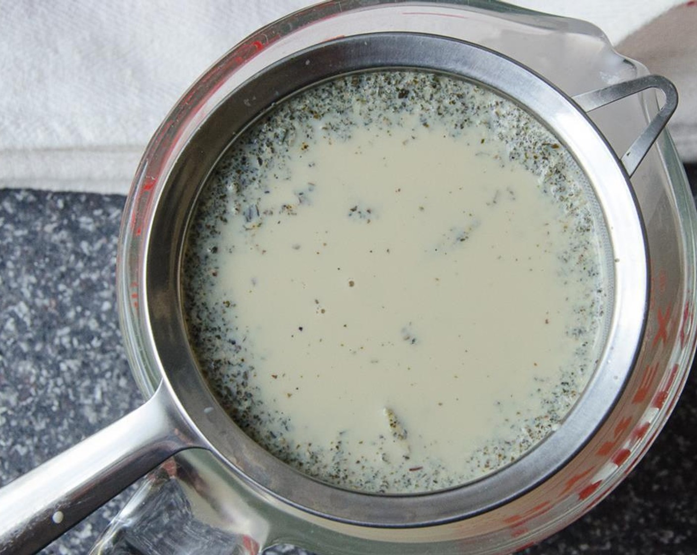 step 3 Place a fine mesh strainer over a 2 cup (or greater) glass measuring cup with a pouring lip. Pour the milk and tea leaves through the strainer, pressing on the solids to force the milk into the cup.