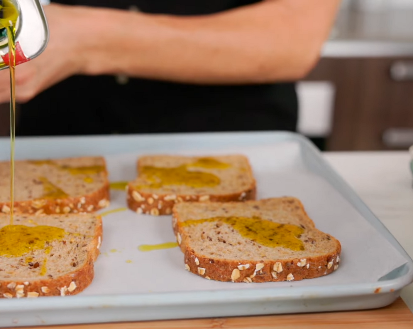 step 2 Place Multigrain Bread (4 slices) onto a baking sheet. Drizzle with Olive Oil (4 Tbsp) and sprinkle with Sea Salt (1/2 tsp) and Ground Black Pepper (1/2 tsp).