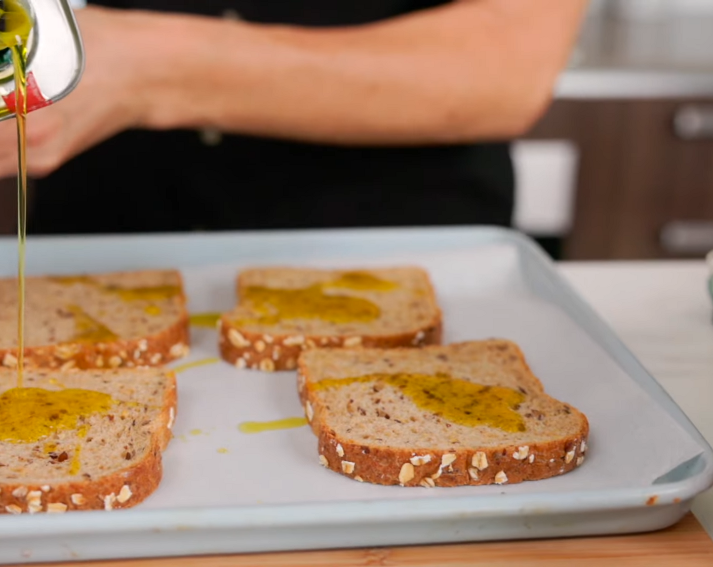 step 2 Place Multigrain Bread (4 slices) onto a baking sheet. Drizzle with Olive Oil (1/4 cup) and sprinkle with Sea Salt (1/2 tsp) and Ground Black Pepper (1/2 tsp).