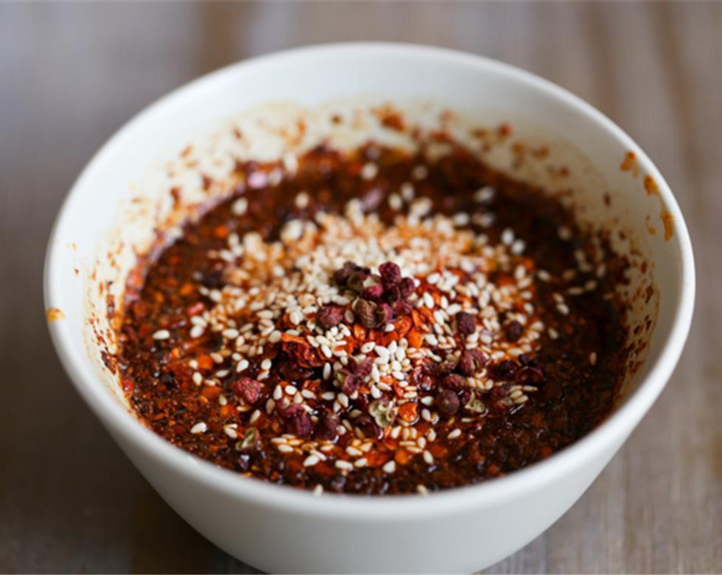 step 5 Add another 2 tablespoons of Red Chili Powder (2 Tbsp), Toasted White Sesame Seeds (1 Tbsp), and Sichuan Peppercorns (1/4 tsp) in the bowl.