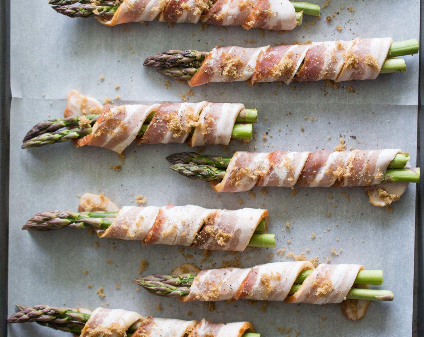 step 2 Wrap Asparagus (1 bunch) in Bacon (10 slices) (2-3 spears of asparagus to one strip of bacon). Sprinkle Brown Sugar (2 Tbsp) and Ground Black Pepper (1 pinch) on top of bacon.