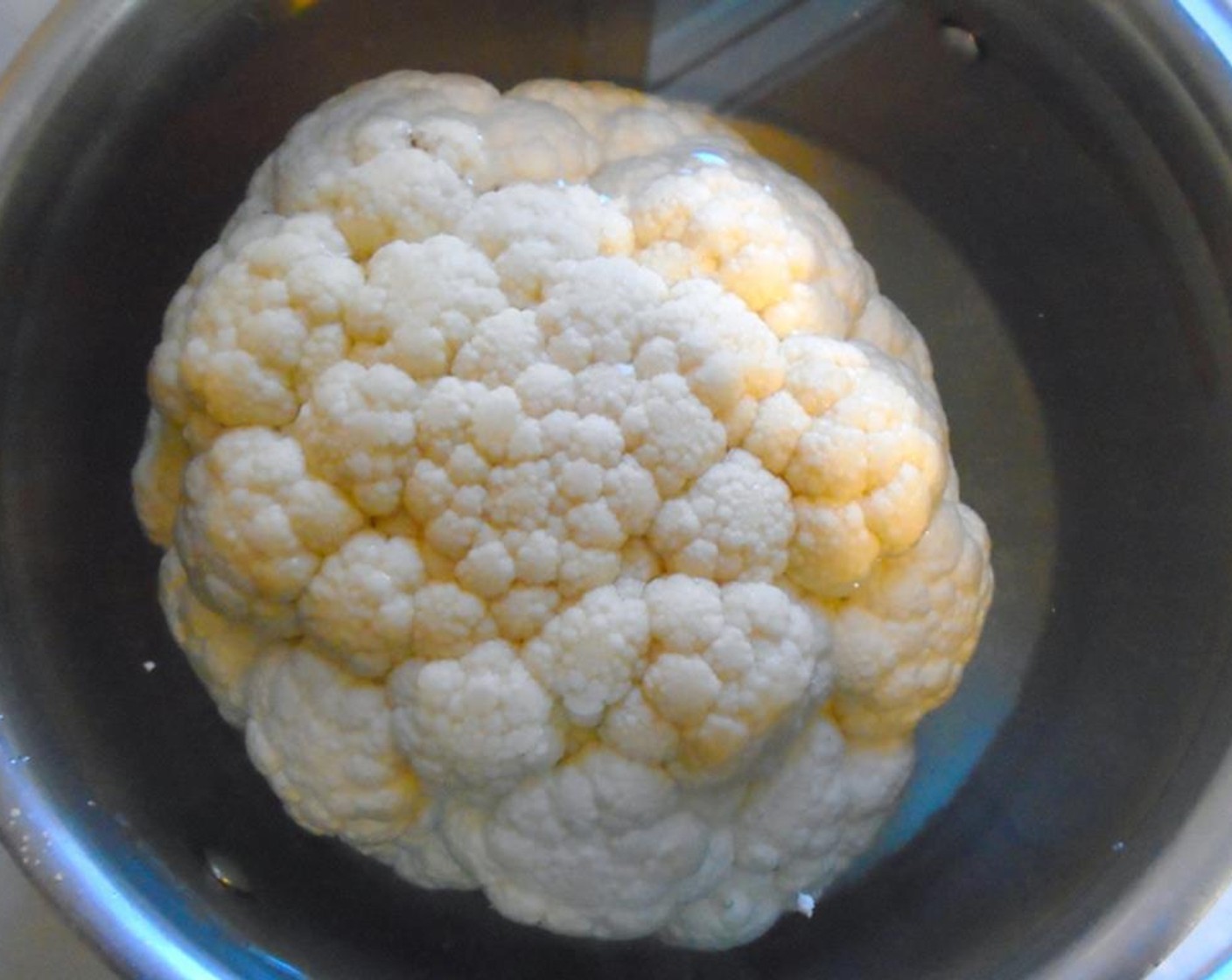 step 6 Place the large head of cauliflower in a cold pot of salted water. Bring to a slow simmer and cook until tender, but not soft for about 5 minutes.