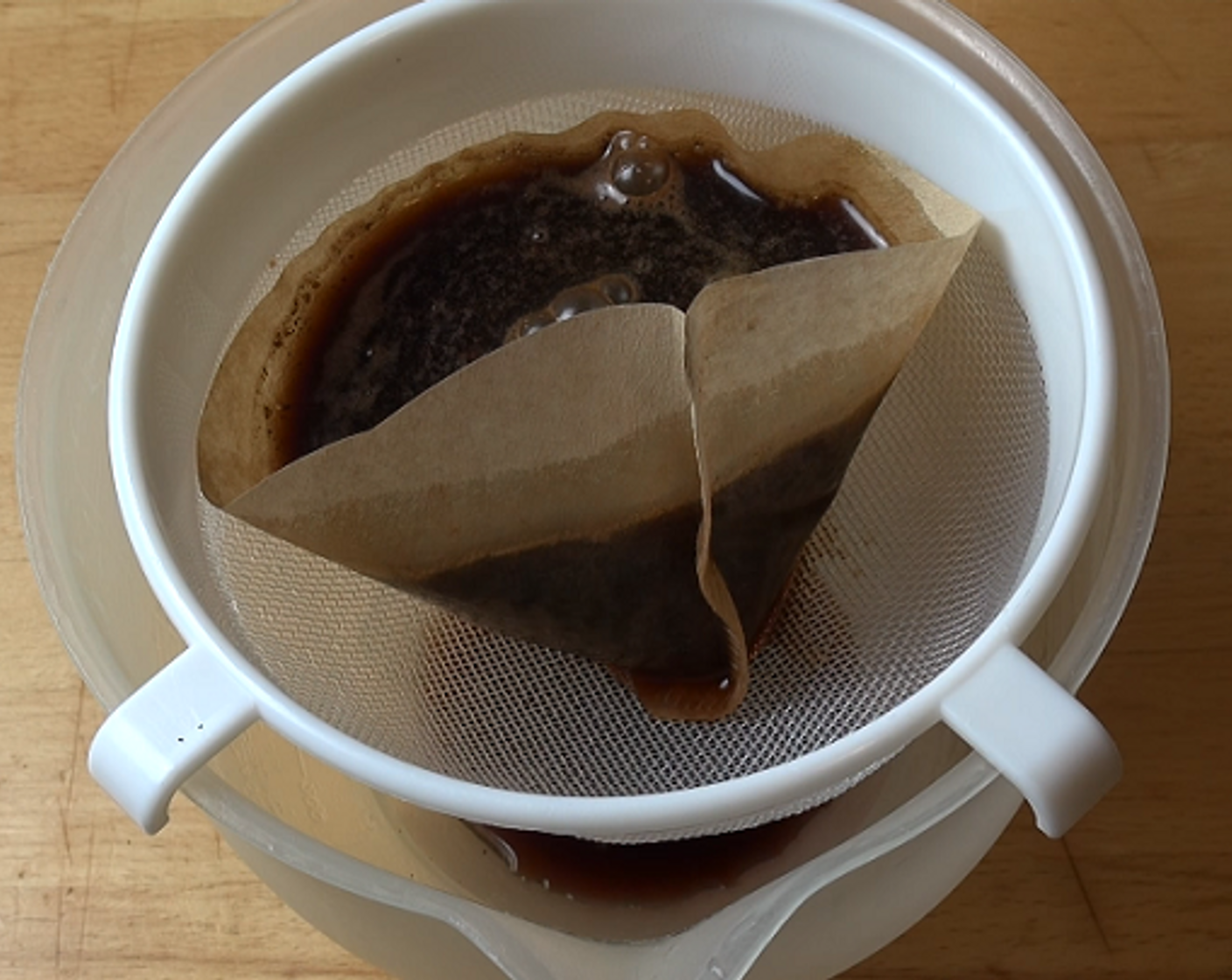step 2 Place a paper coffee strainer in a regular metal strainer, and gently pour the coffee water through both into a large bowl or jug. You don't want any bits getting through, so pour the coffee a little at a time. You will end up with about 2 cups of coffee concentrate.