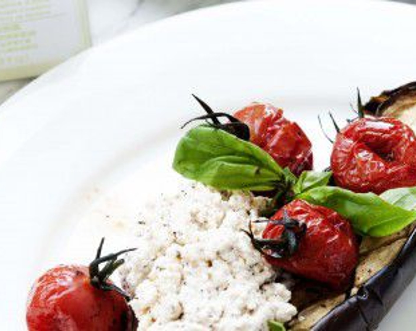 step 7 To serve, plate half an eggplant, some roasted tomatoes and a heaping tablespoon of ricotta. Drizzle more Extra-Virgin Olive Oil (2 Tbsp) and decorate with some Fresh Basil Leaves (to taste).