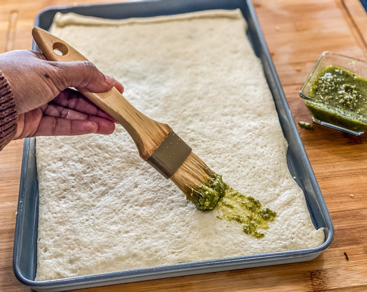step 3 Brush 1 tablespoon of pesto sauce evenly over all the pizza dough.