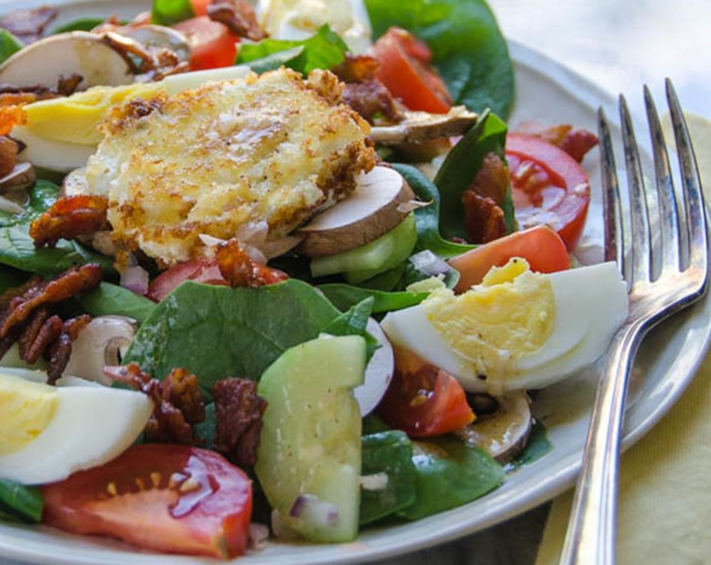 step 10 Pour the warm dressing over the salad and toss to combine. Divide the salad onto 4 plates. Sprinkle each salad with bacon. Divide eggs among the plates and top each salad with the warm goat cheese. Serve.