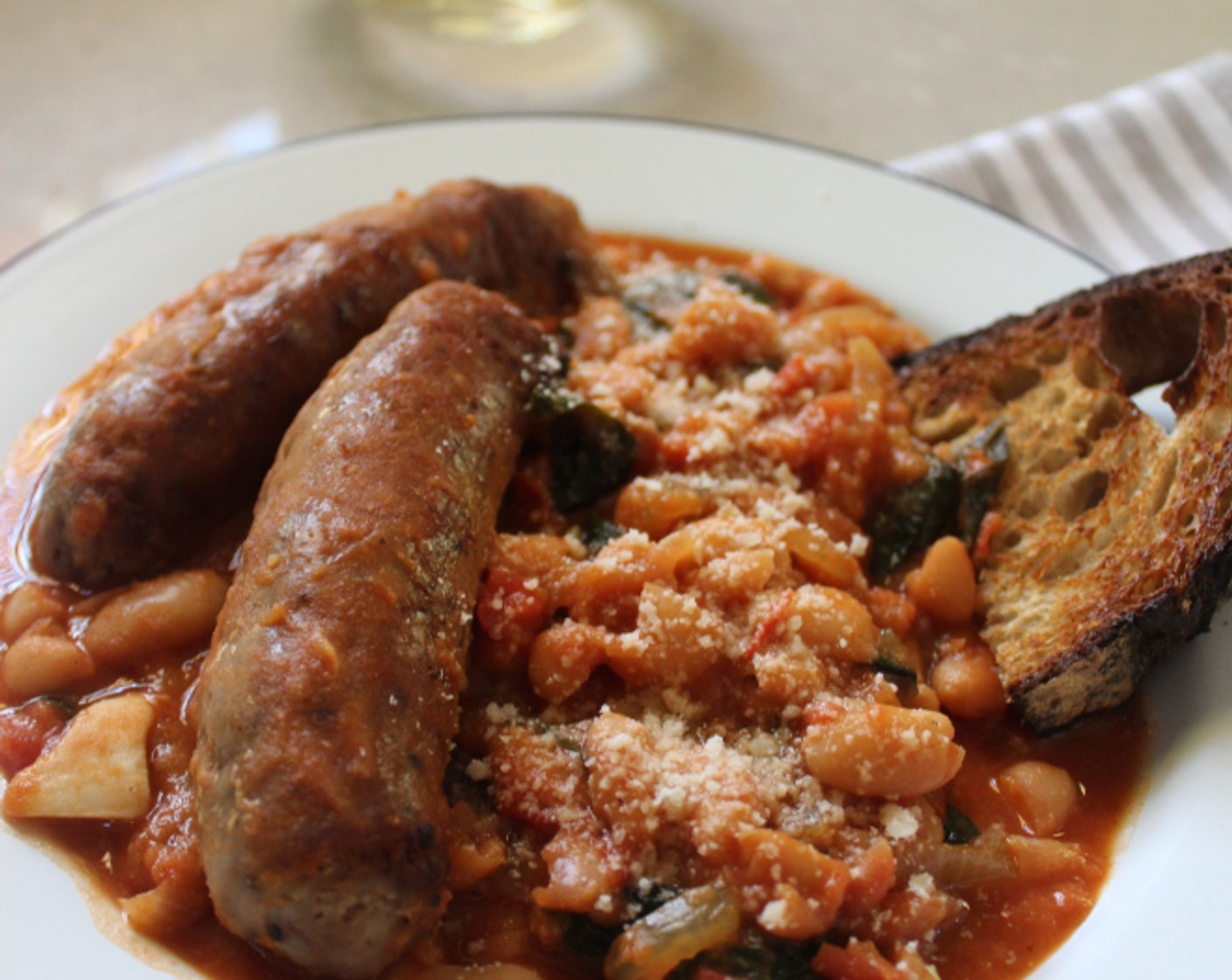 step 8 To serve, spoon some of the beans into the bottom of a shallow bowl or deep plate. Top with a sausage and sprinkle with Parmesan Cheese (to taste). Serve hot with Rustic Bread (to taste) on the side.