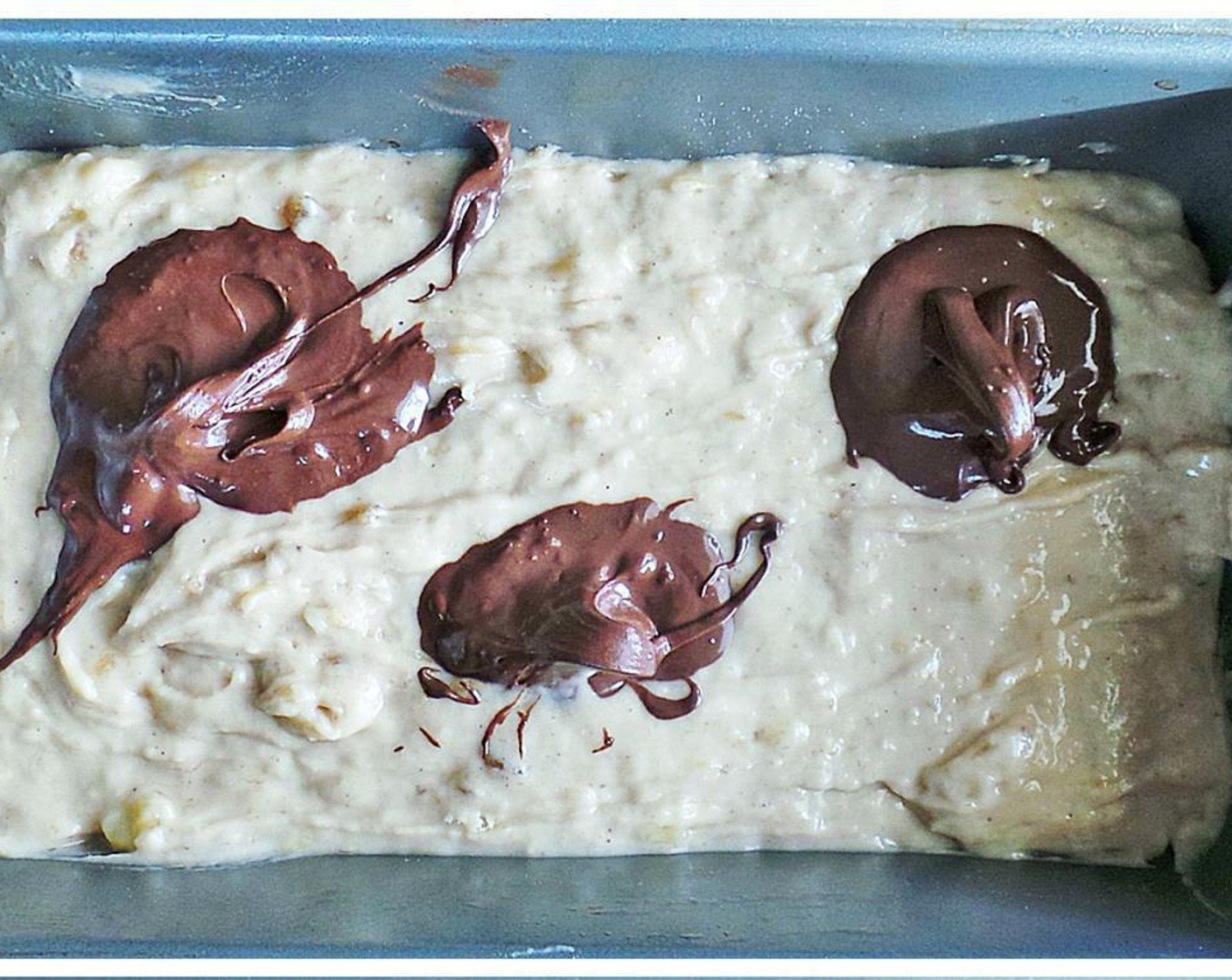 step 5 Pour the bread batter into a greased loaf pan and dollop with the melted semi-sweet chocolate.