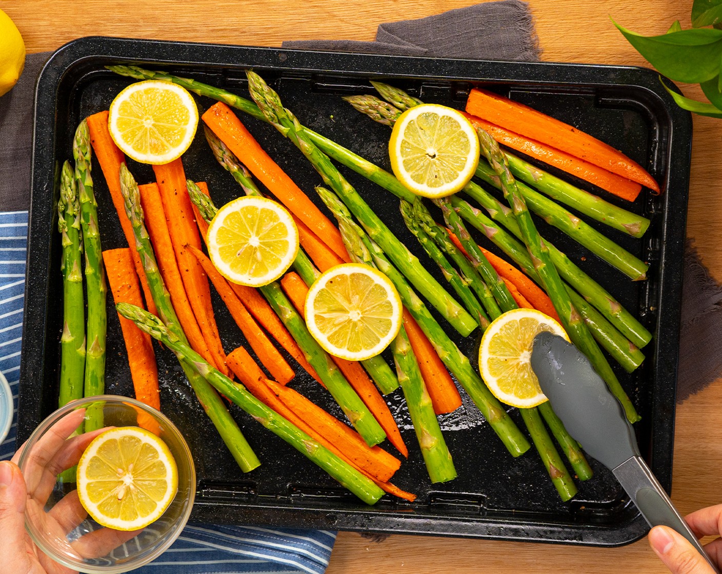 step 3 Dann das Blech aus dem Ofen nehmen. Den Spargel, grün (1 Bd.) und die Zitrone (1) auf dem Blech verteilen und gut mischen, sodass das Gemüse mit Olivenöl ummantelt ist. Das Ganze zurück in den Ofen geben und für weitere 5–10 Minuten goldbraun garen.