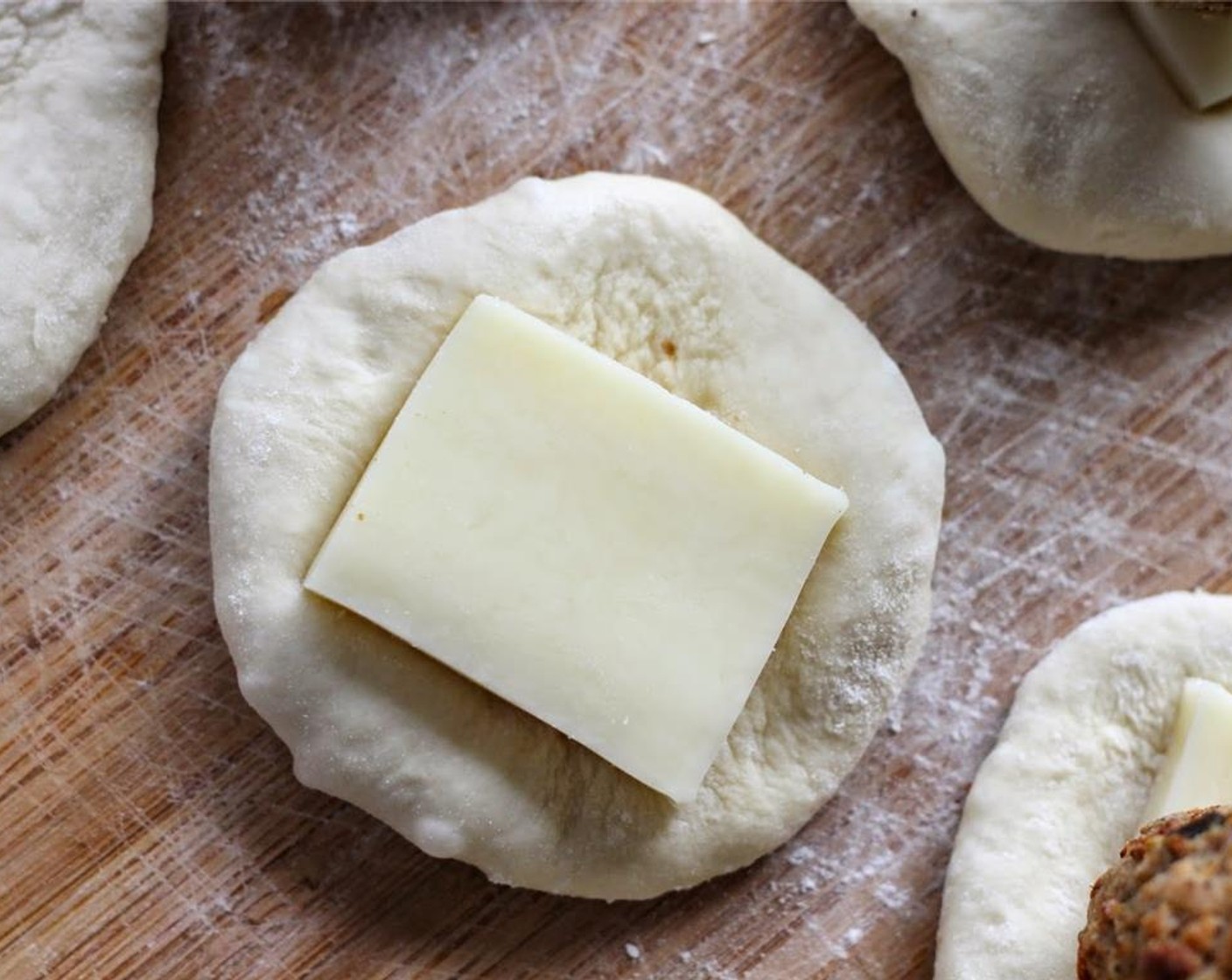 step 1 Preheat oven to 375 degrees F (190 degrees C). Roll and stretch out each Frozen Dinner Rolls (24) until it is about 4 inches across. Top with a slice of Mozzarella Cheese (24 slices).