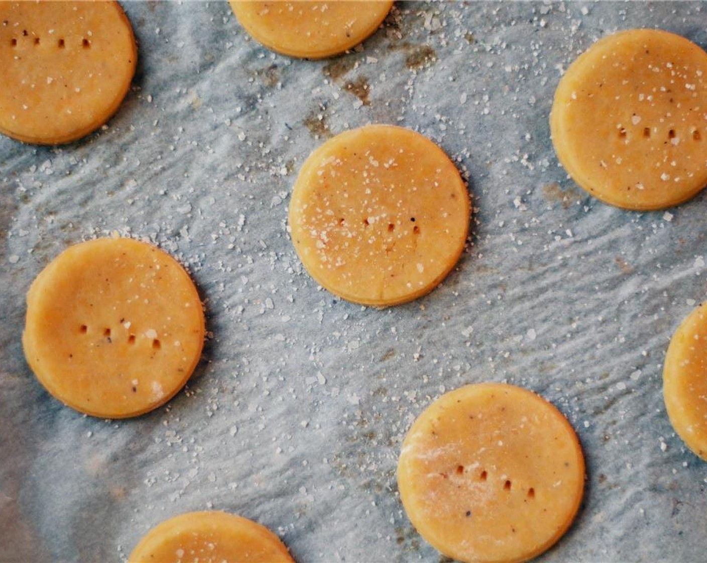 step 6 On a lightly floured surface, roll dough out until it is very thin, about a 1/8-inch thickness. Use a small cookie cutter to cut rounds and place them on a prepared bakings sheet. Using a fork, prick holes into the top of the crackers.