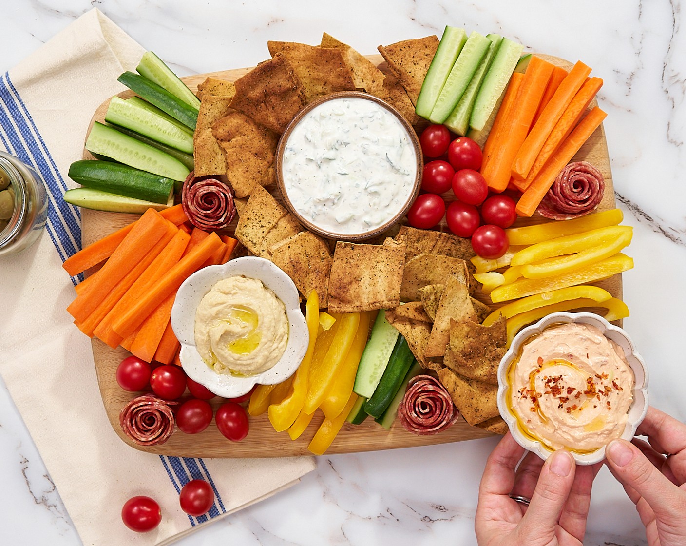 step 10 Add the Hummus (1 cup), tzaziki, whipped feta, and Pimento Stuffed Green Olives (1 3/4 cups). Fill in any holes with more veggies or chips, then serve!