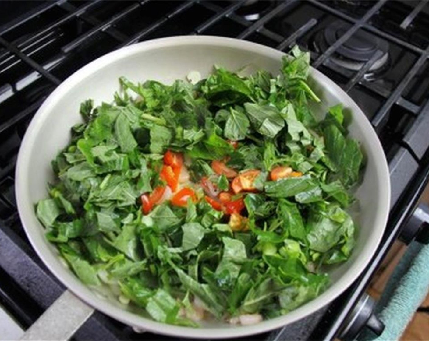 step 3 Turn the heat up to medium high and add the Jamaican Callaloo (30 cups), Tomato (1), Scotch Bonnet Pepper (1/4), Fresh Thyme (2 sprigs), and Sea Salt (1/4 tsp). After a couple minutes, add the Water (1/2 cup) and cook until tender.