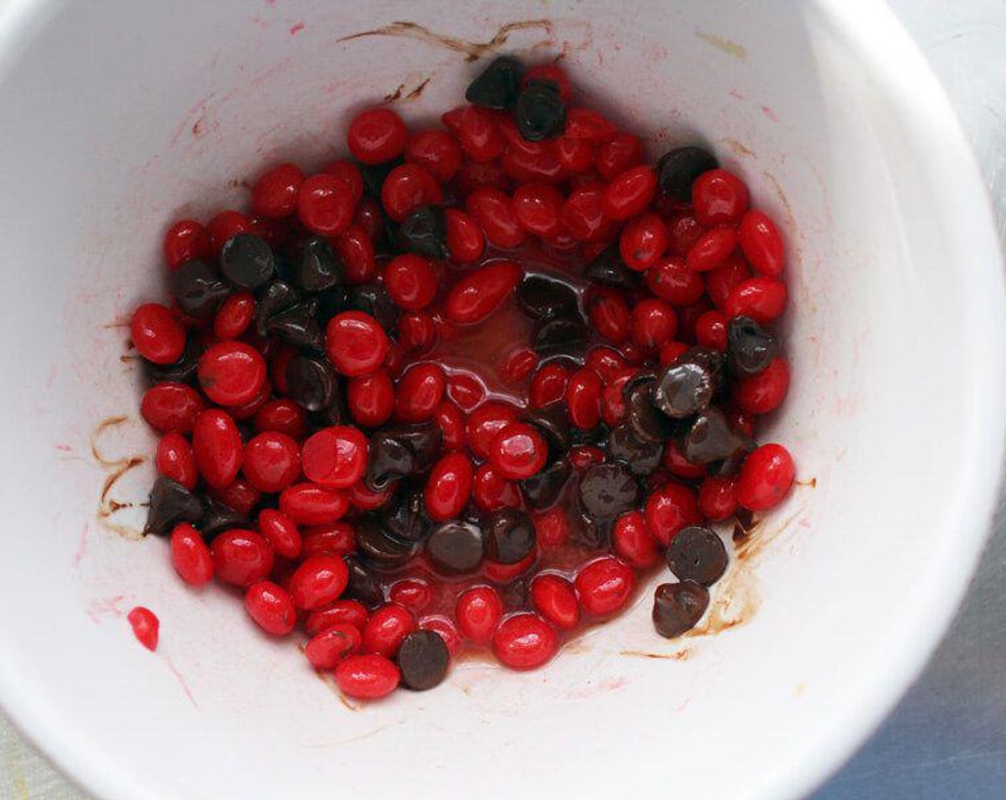 step 6 In the empty chocolate bowl, stir together the remaining Semi-Sweet Chocolate Chips (1 cup), Butter (3 Tbsp) and the Red Hots® Cinnamon Candy (3/4 cup). Microwave in 30-second increments, stirring after each time until the candies start to get gooey and soft. Add the Water (1/4 cup), stir and cook until smooth.