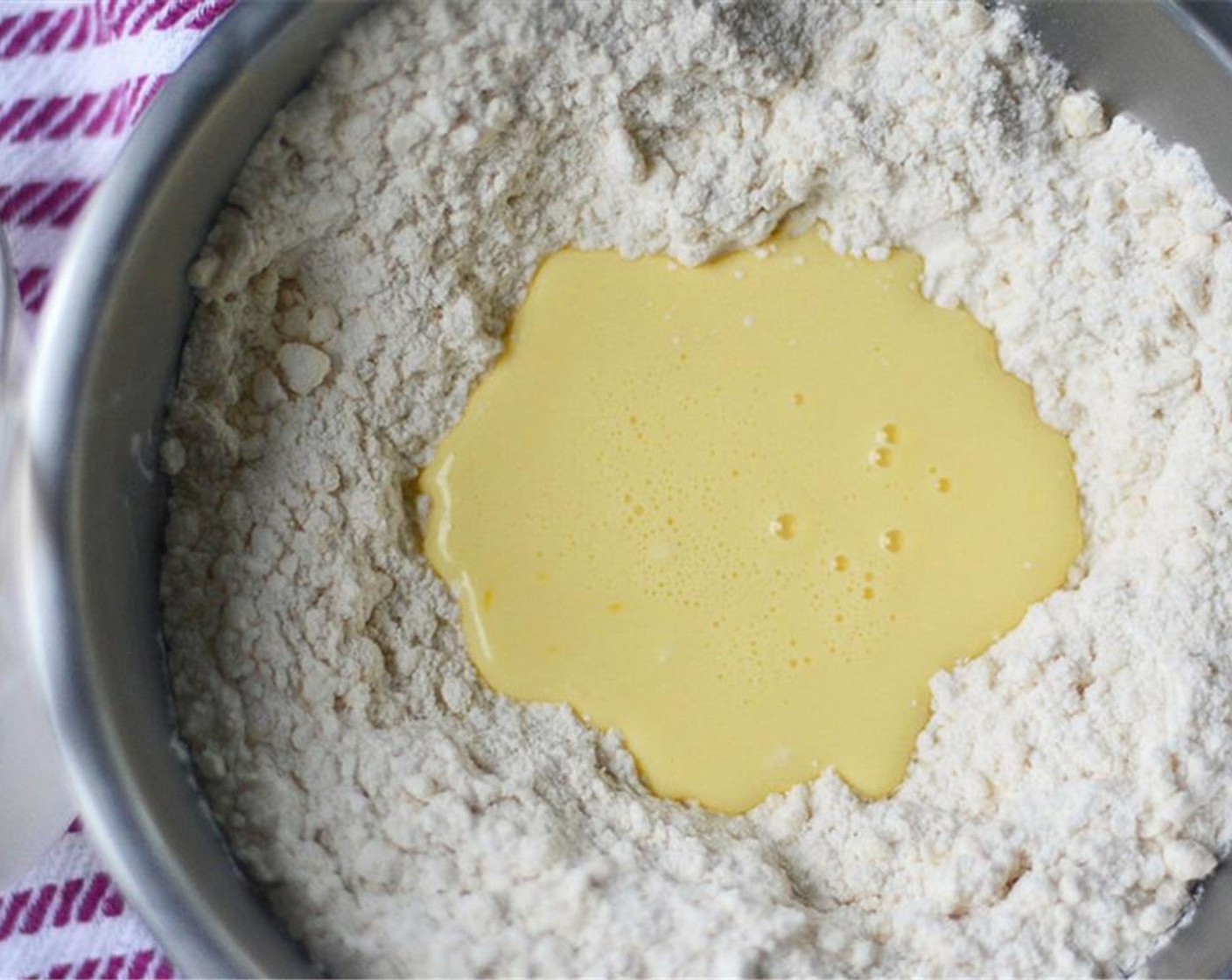 step 5 Create a well in the middle of the flour/butter mixture and pour in buttermilk-eggs. With a fork, bring flour into the buttermilk-egg and stir until dough begins to form.