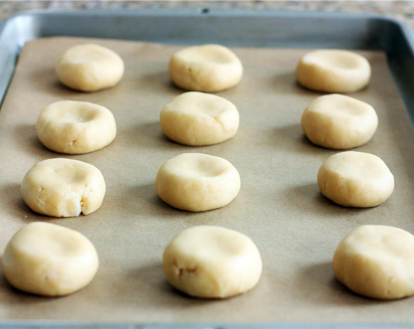 step 7 Press the heel of your hand gently onto each ball so that it forms a thick disc. Bake at 350 degrees F (180 degrees C) for about 11-12 minutes until the bottom edges have barely begun to brown and the tops still glisten slightly.