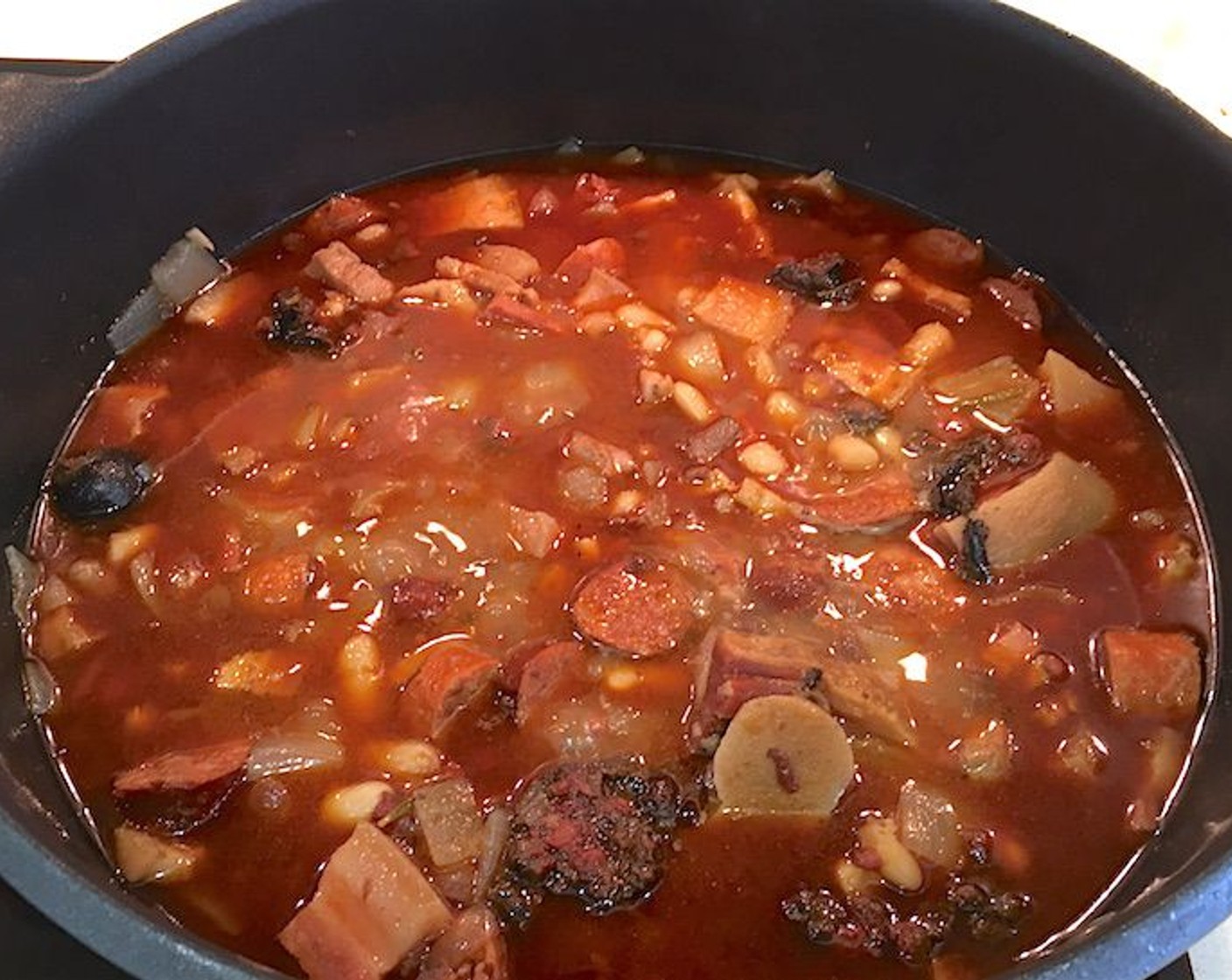 step 10 Add onions and garlic to pot. Add Salt (to taste) and Ground Black Pepper (to taste).  Cook for another 30 minutes or until pork and bacon are tender and sausage is cooked through.