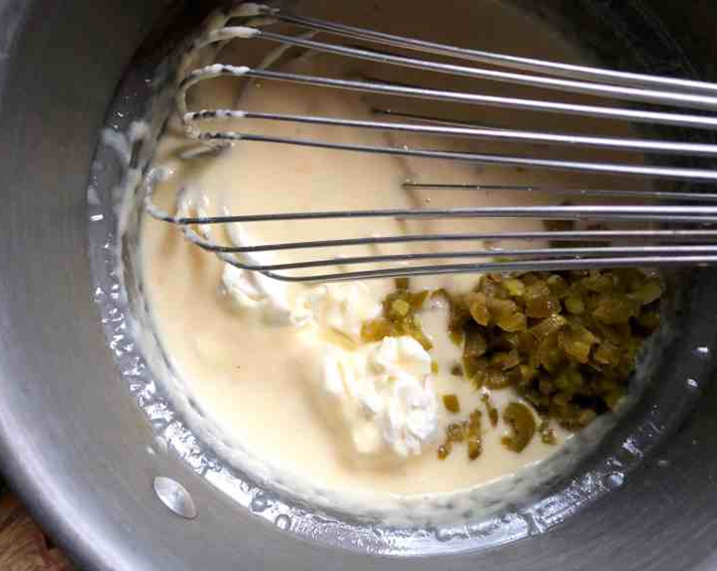step 7 Whisk together the Pepper Jack Cheese (1 packet) and Evaporated Milk (1/2 cup) in the top of a double boiler over simmering water. Whisk until smooth for 3 to 4 minutes. Remove from heat, stir in the Cream Cheese (4 Tbsp) and Pickled Jalapeño Pepper (1/4 cup).