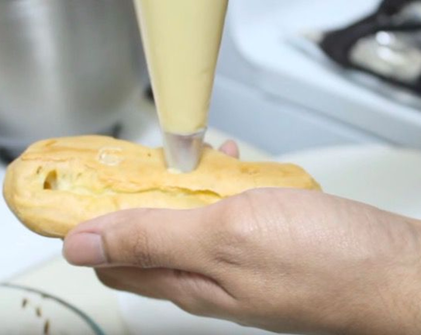 step 11 Transfer custard to a piping bag. Make a small hole in each eclair and fill it with the custard. Dip one side of each eclair into the chocolate.