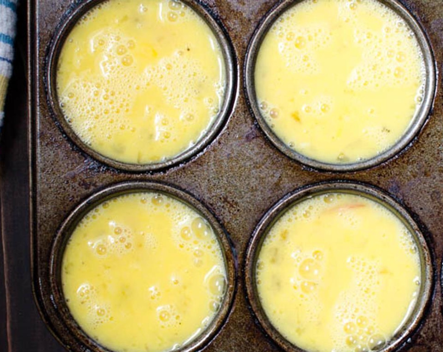 step 6 Whisk the Eggs (4) in a small bowl and season with the Salt (1/2 tsp) and Freshly Ground Black Pepper (1/4 tsp). Divide the eggs among the muffin tins.