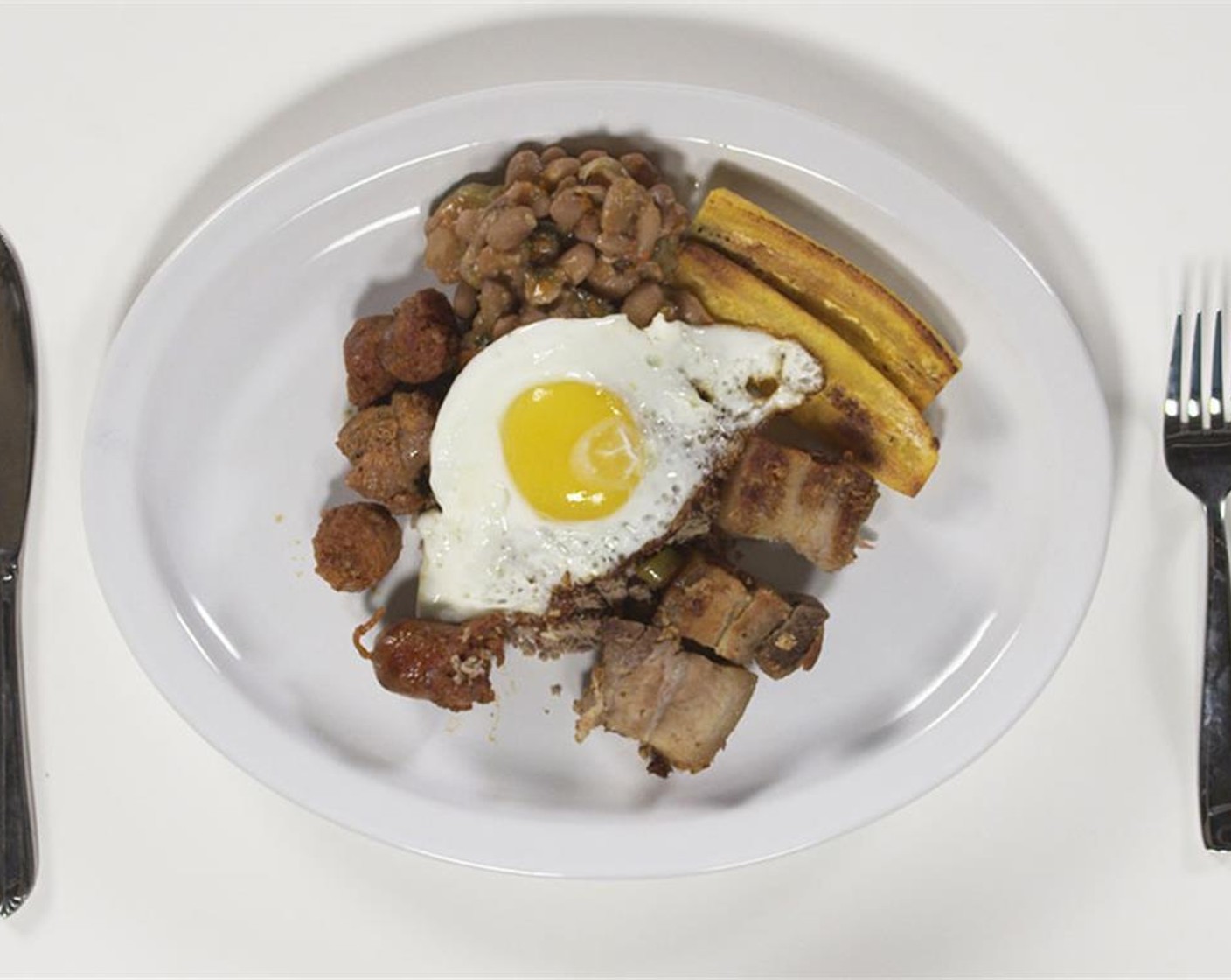 step 14 Fry your Eggs (4), reheat beans, and plate with chorizo, powdered beef, pork belly, plantains and hogao!