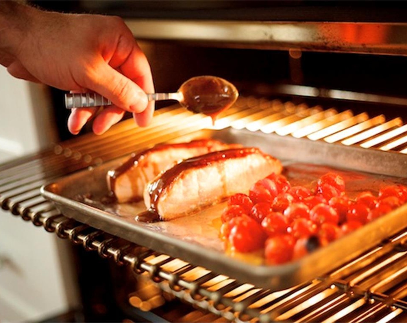 step 11 Pat dry Salmon Fillets (2) with paper towels. Place on one half of a rimmed baking sheet lined with foil and spread only half of the maple glaze evenly over each fillet. Place the seasoned tomatoes on the other half of the baking sheet and place under broiler.