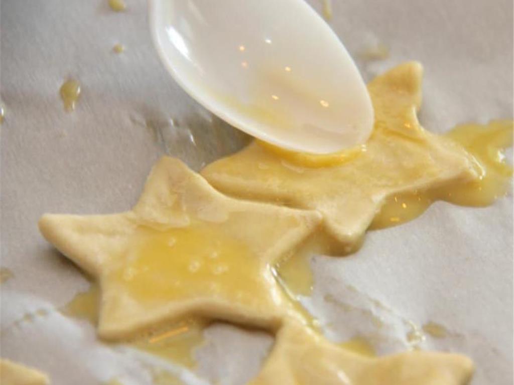 Step 4 of Easy Peasy Cheesy Puffs Recipe: Lay shapes onto a sheet of parchment paper on your baking pan and brush with egg wash.