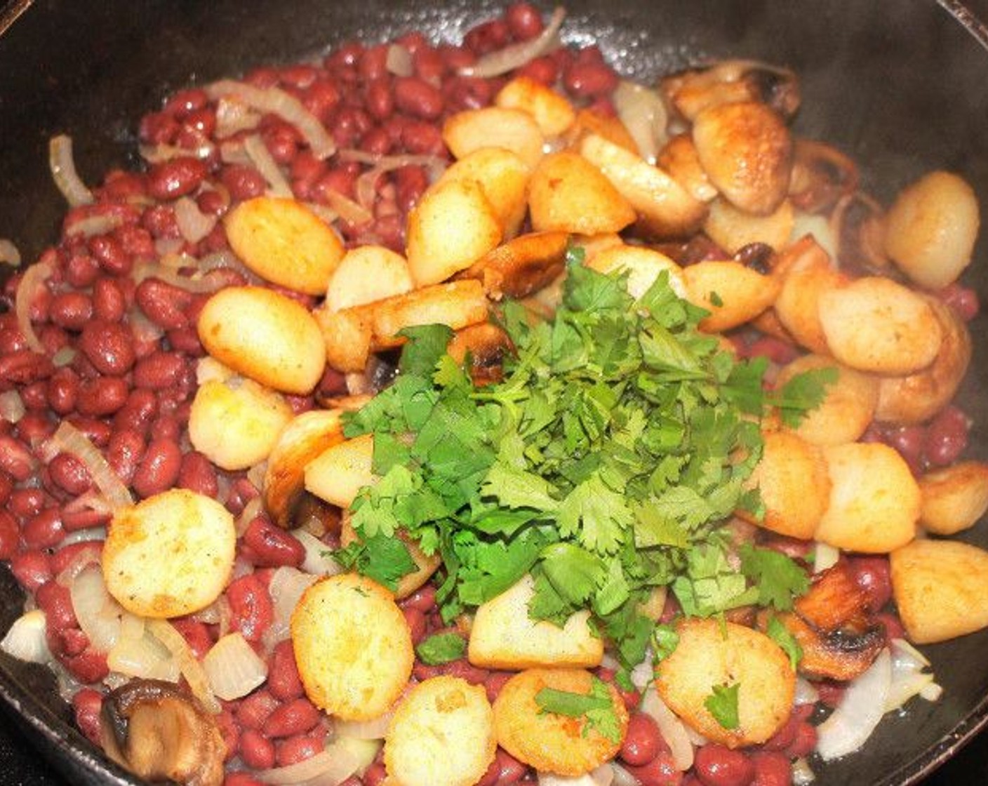 step 10 Add the onion and bean mix to the potato and mushroom mix, then add the cilantro and stir to combine.