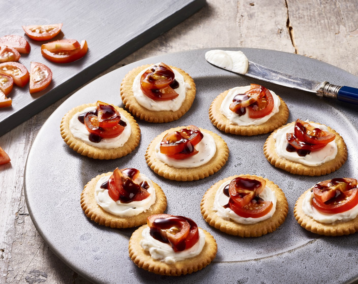 step 1 Spread approx. 1 tsp of Garlic & Herbs Cream Cheese (3/4 cup) onto each Ritz® Crackers (25), then top with a few pieces of Cherry Tomatoes (9) and a drizzle of Balsamic Glaze (2 Tbsp).