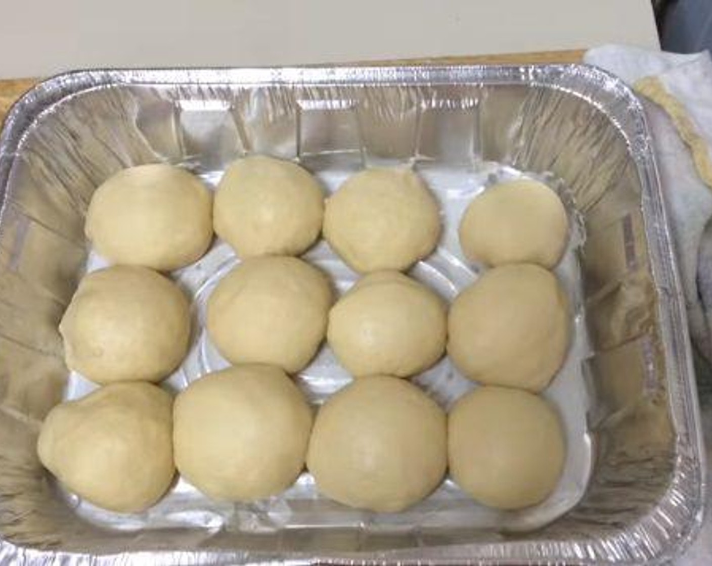 step 4 Form the dough into an elongated bread shape, and cut it into 12 equal pieces. Form each piece into a ball shape, and place it into a baking dish. Cover the buns with a towel, and place them in a warm place for about an hour.