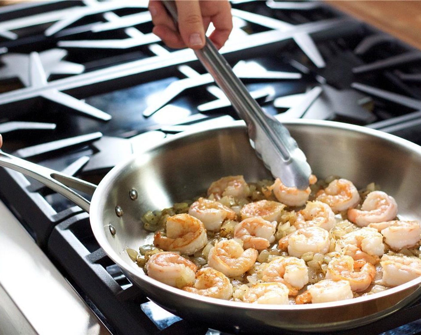 step 5 Meanwhile, pat dry Shrimp (20) with paper towels, and set aside. In a large saute pan over medium high heat, add Olive Oil (2 Tbsp), garlic, onion, Salt (1/2 tsp) and Ground Black Pepper (1/4 tsp). Cook all together, stirring frequently.