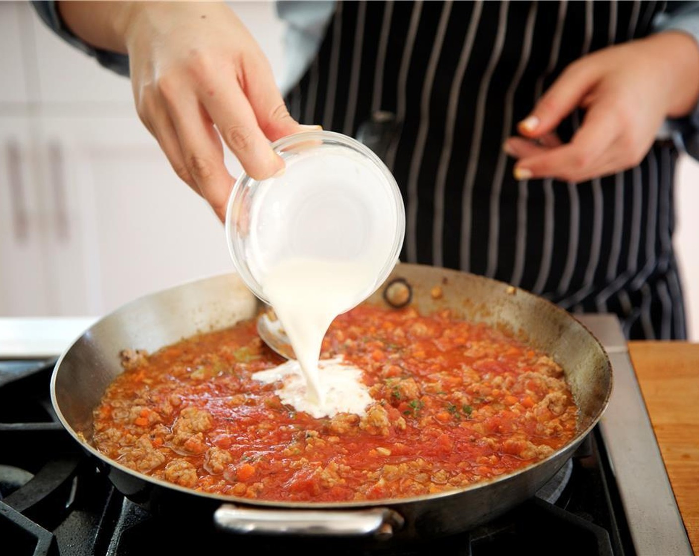 step 9 Deglaze the pan with White Cooking Wine (1/4 cup). Add Canned Crushed Tomatoes (3 1/3 cups), Bay Leaf (1), thyme and Whipping Cream (1/4 cup). Stir constantly.