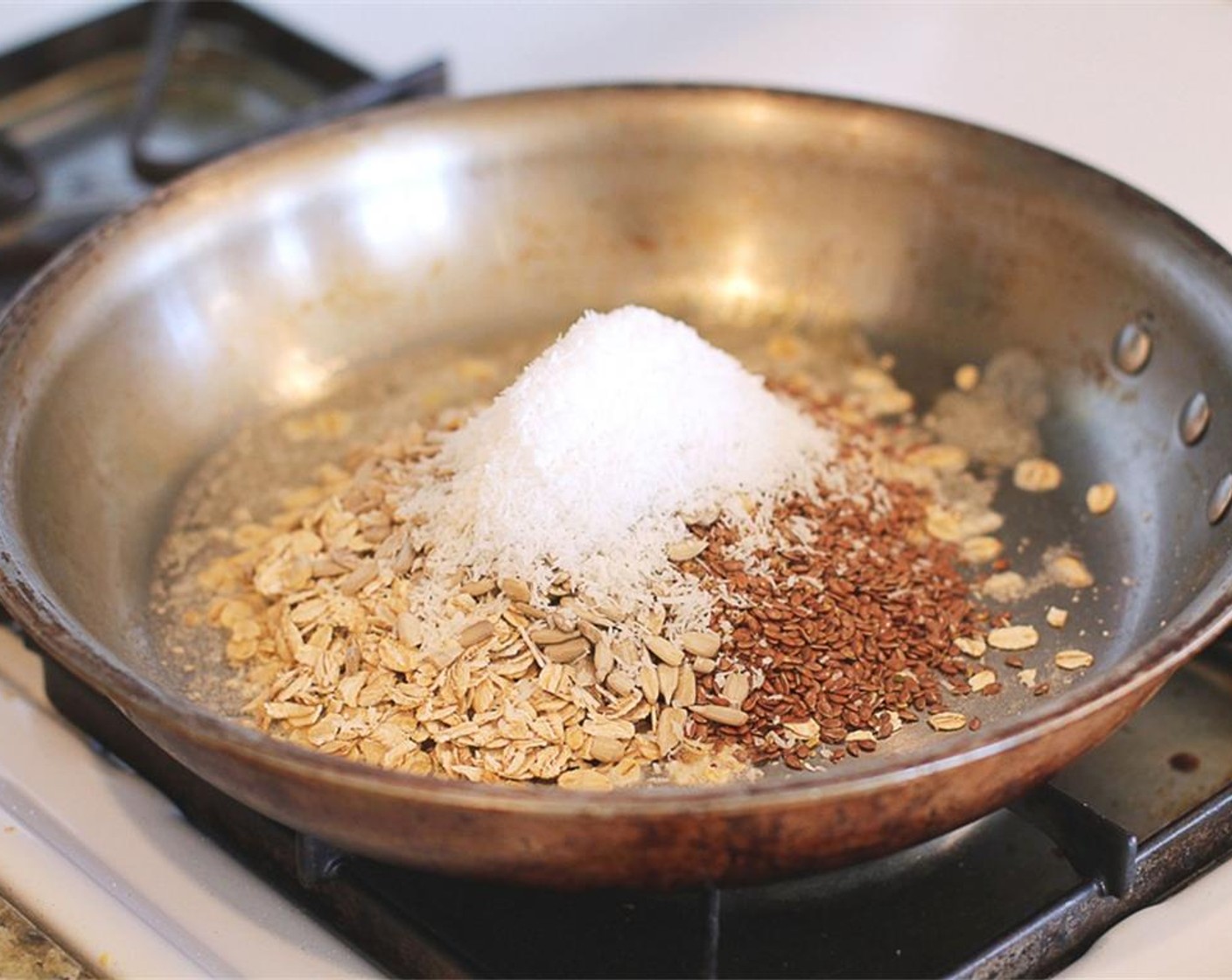 step 2 Then add Old Fashioned Rolled Oats (2/3 cup), Flaxseeds (1/3 cup), and Sunflower Seeds (1/3 cup). Toss it all around the pan so it gets coated in the butter.