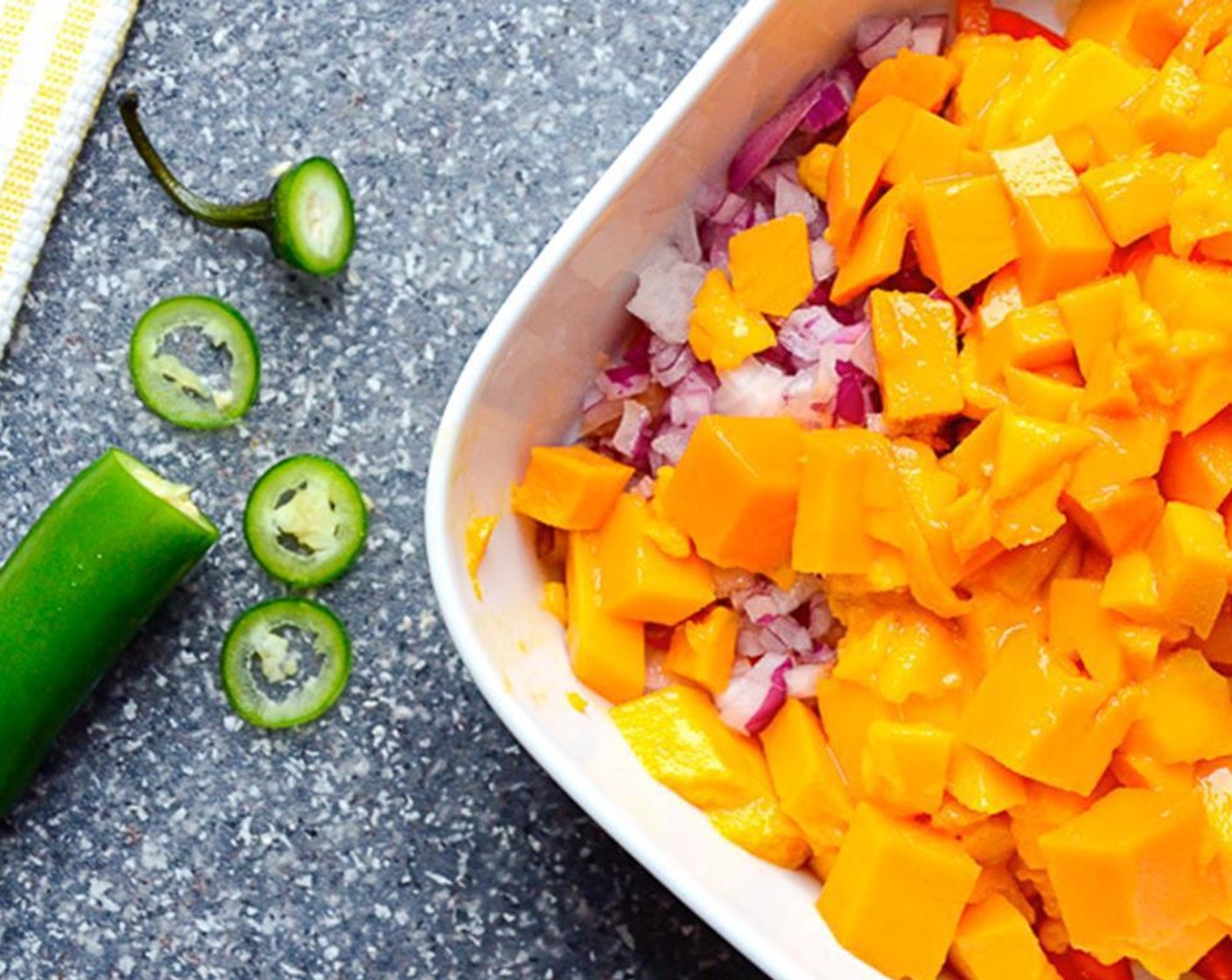 step 5 In a small bowl, combine the Mangoes (2), the minced bell pepper, Red Onion (1/4), Serrano Chili (1), zest and juice of the Lime (1) and Salt (1 pinch). Stir to combine and set aside.