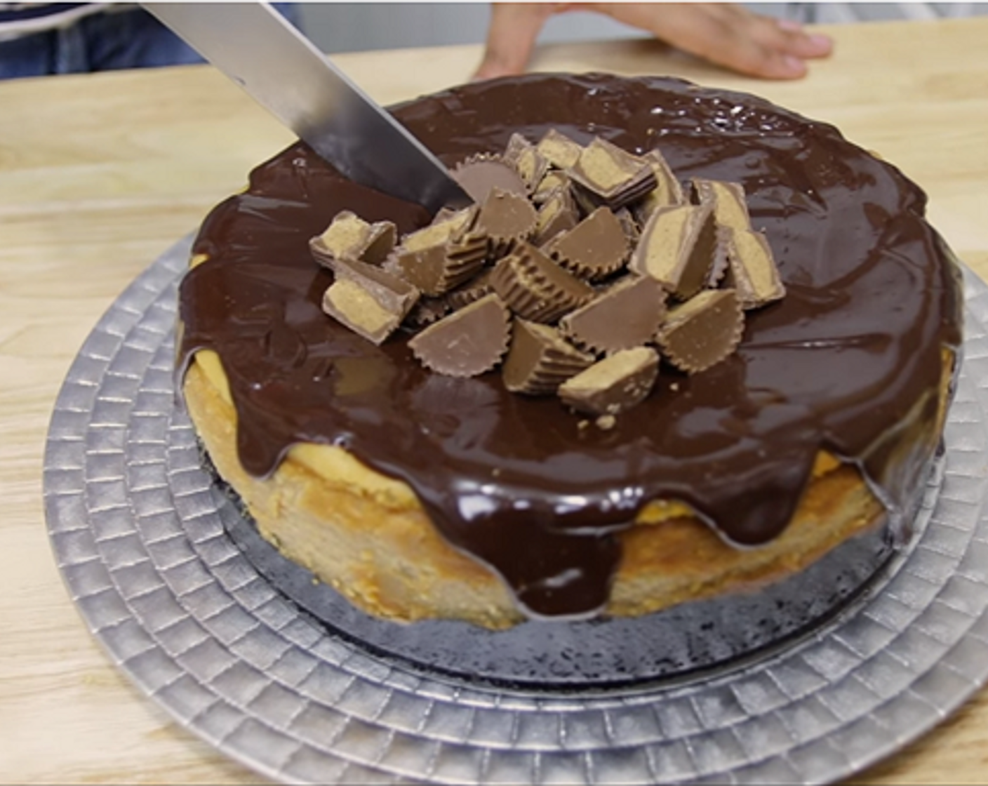 step 10 Run a knife around the cheesecake pan to release it. Pour over chocolate ganache, spread evenly on top. Decorate with Reese's peanut cup.