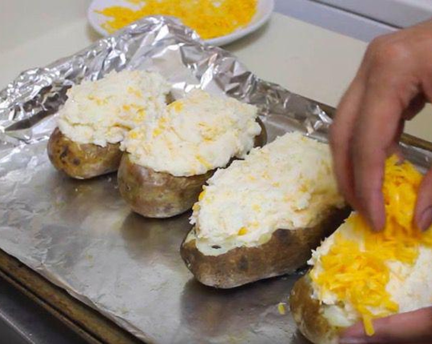 step 4 Spoon in the potato mixture into each of the potato canoes. Top with the rest of the Sharp Cheddar Cheese (1/2 cup). Leave some cheddar for topping. Cook at 400 degrees F (200 degrees C) for 15-20 minutes.