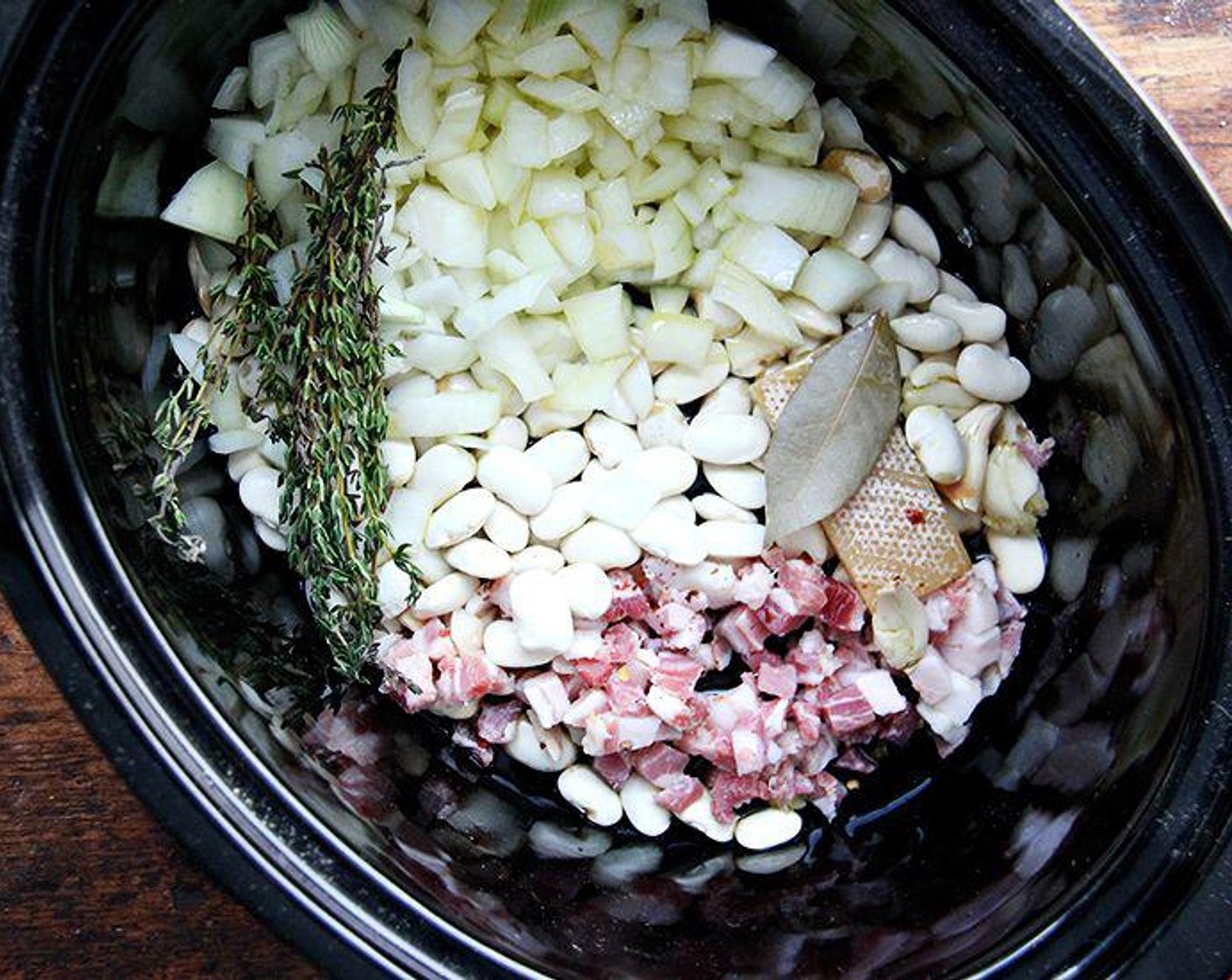 step 1 Place the Dry White Beans (1 cup), Bay Leaf (1), Crushed Red Pepper Flakes (1 pinch), Garlic (2 cloves), Onions (2), Fresh Thyme (3 sprigs), and Pancetta (1/4 cup) into your crockpot.