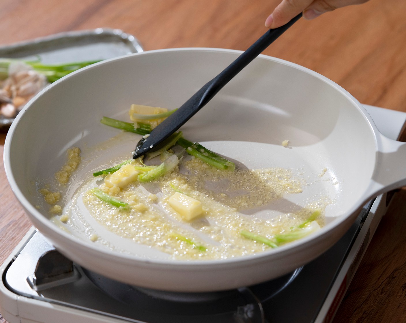 step 2 In a frying pan, heat the Butter (2 Tbsp) over medium high heat. Then stir in the Garlic (3 cloves) and the white part of the Scallions (3 stalks). Cook for about 1 minute until softened and fragrant.