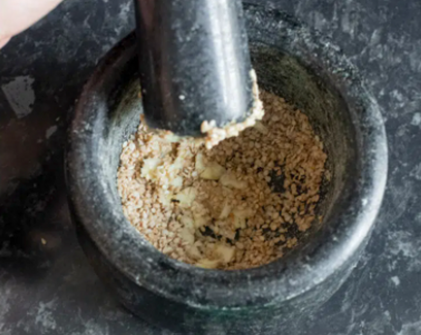 step 1 Lightly crush the White Sesame Seeds (2 Tbsp) with a pestle for 1-2 minutes. Add the Garlic (1 clove) and grind for another 1-2 minutes. The texture should be a combination of powder and fine pieces, not a paste.