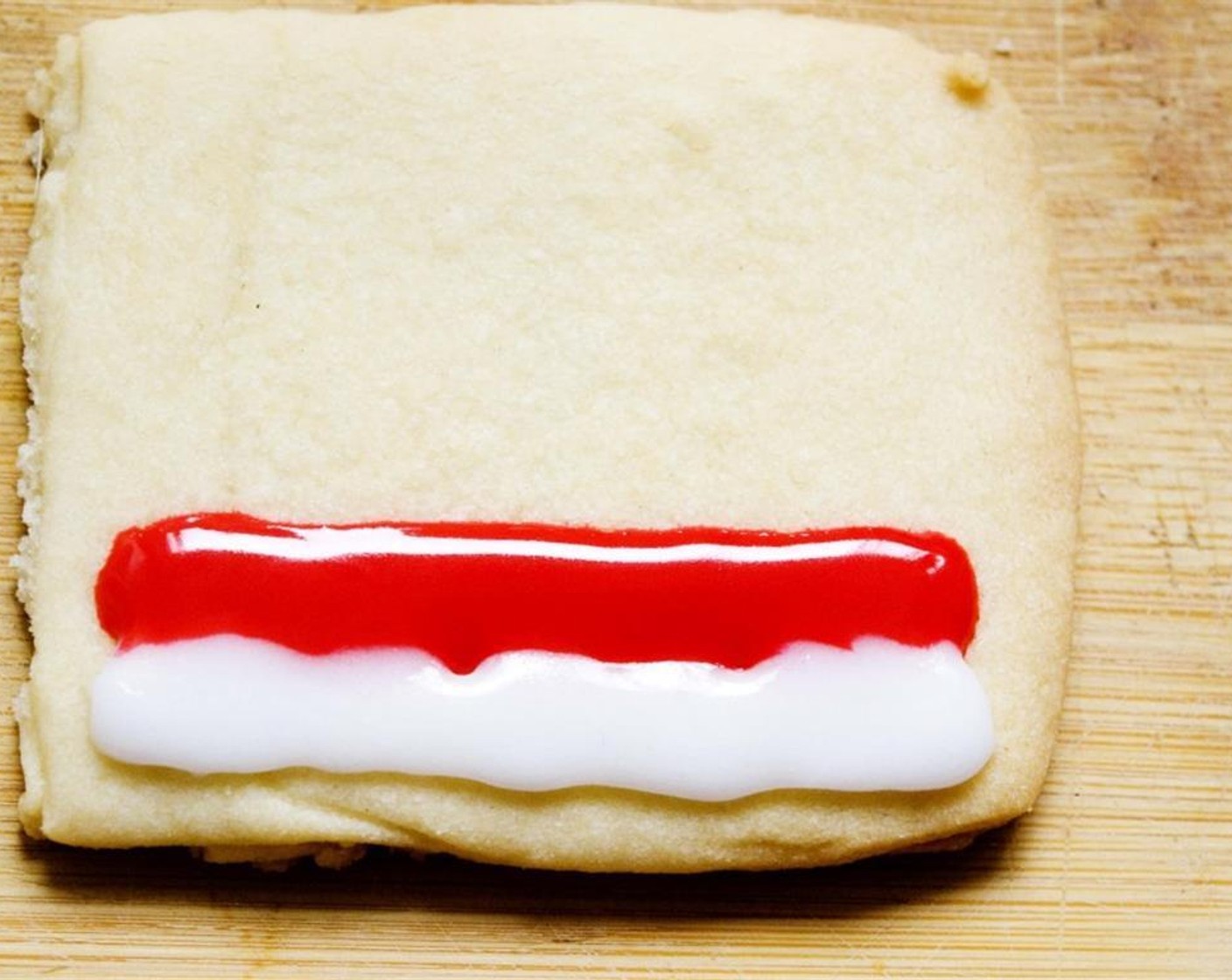 step 10 Then, pipe even lines on each cookie, alternating between the white and red icing.
