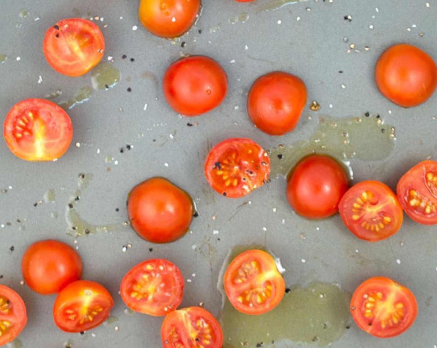 step 6 Cut Cherry Tomatoes (300 g) in half lengthwise. Place cut side down onto baking sheet. Drizzle with Extra-Virgin Olive Oil (1 Tbsp) and season with Salt (1/2 tsp) and Ground Black Pepper (1/4 tsp).