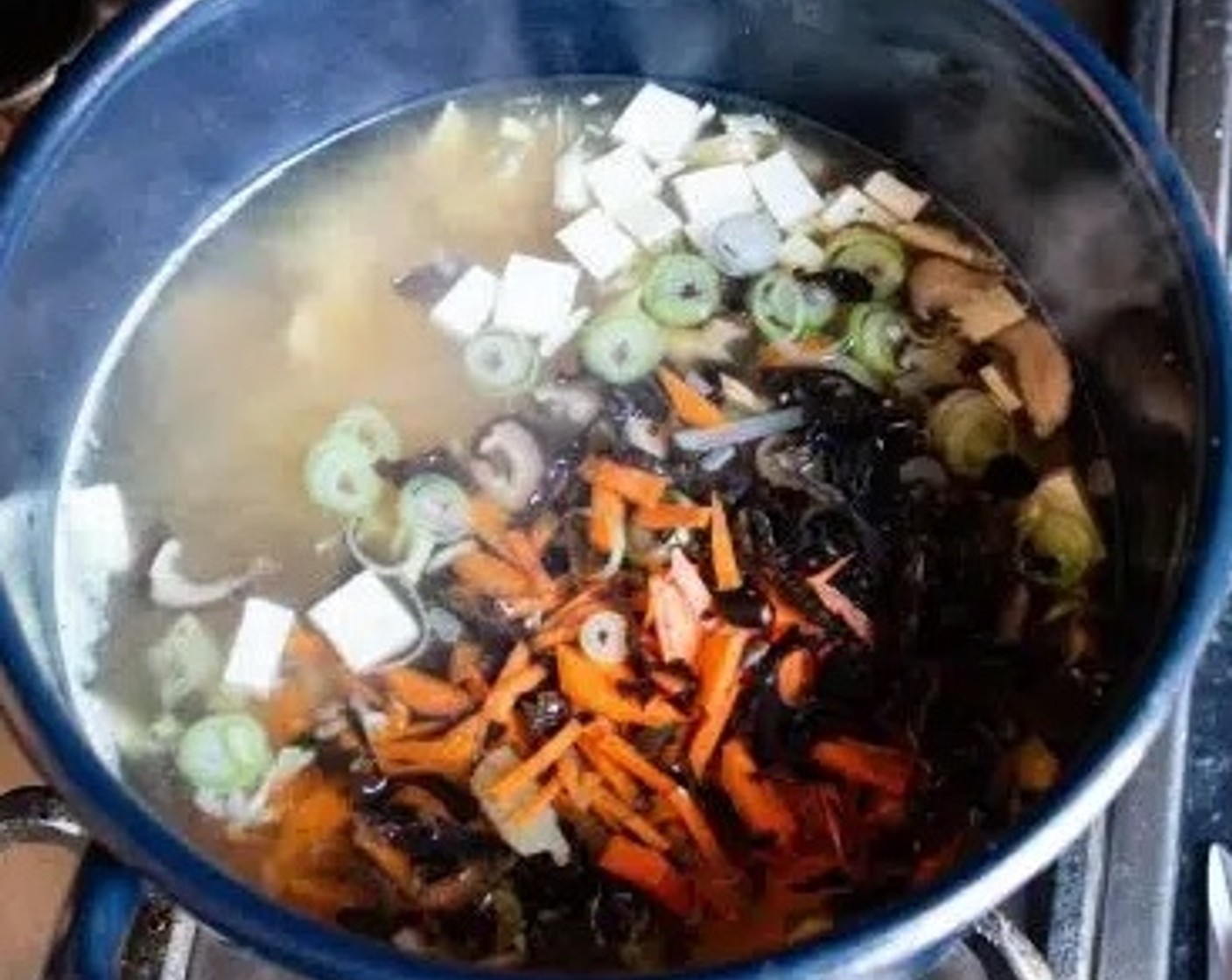 step 4 Once the tofu stick pieces are completely soft, add Carrot (1/4 cup), Bamboo Shoots (1/4 cup), Dried Shiitake Mushrooms (2 Tbsp), Wood Ear Mushrooms (1 tsp), Silken Tofu (3 oz), and the white part of the Spring Onion (1/2).