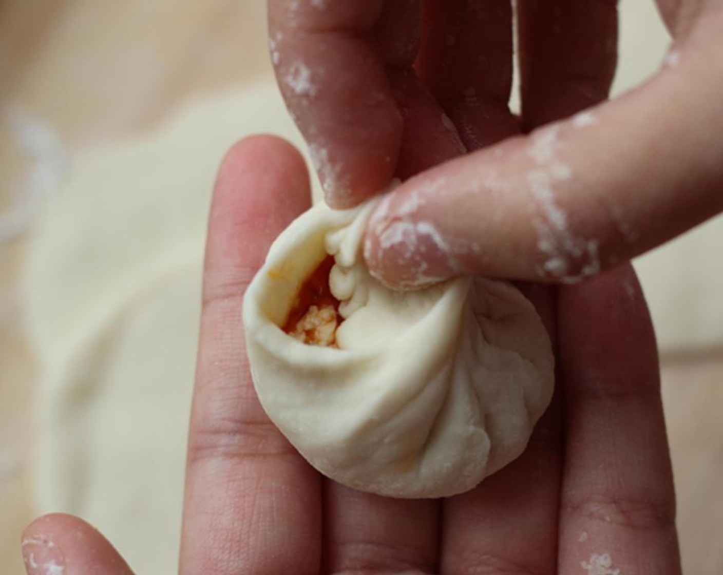 step 7 To fold the baozi, fix the starting point with the thumb of right hand and begin to fold the edge counterclockwise. Move the thumb slowly in the process.