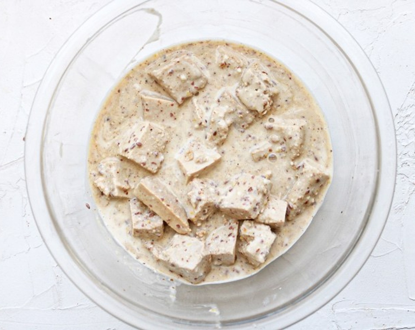 step 6 If you are using a bowl, gently fold in the marinated tofu cubes until they are well coated with the batter. If you are using a Tupperware container, place the lid on securely then gently shake until your tofu is coated.